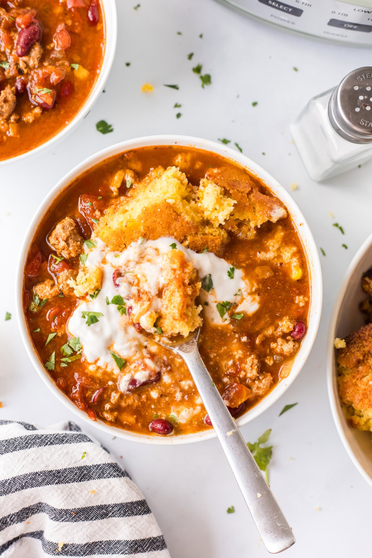 This Easy Slow Cooker Chili is the ultimate comfort food — loaded with ground beef or turkey, beans, and bold spices. A simple, hearty meal that’s perfect for cozy nights, game days, or meal prep! Hearty crockpot chili topped with sour cream and cornbread