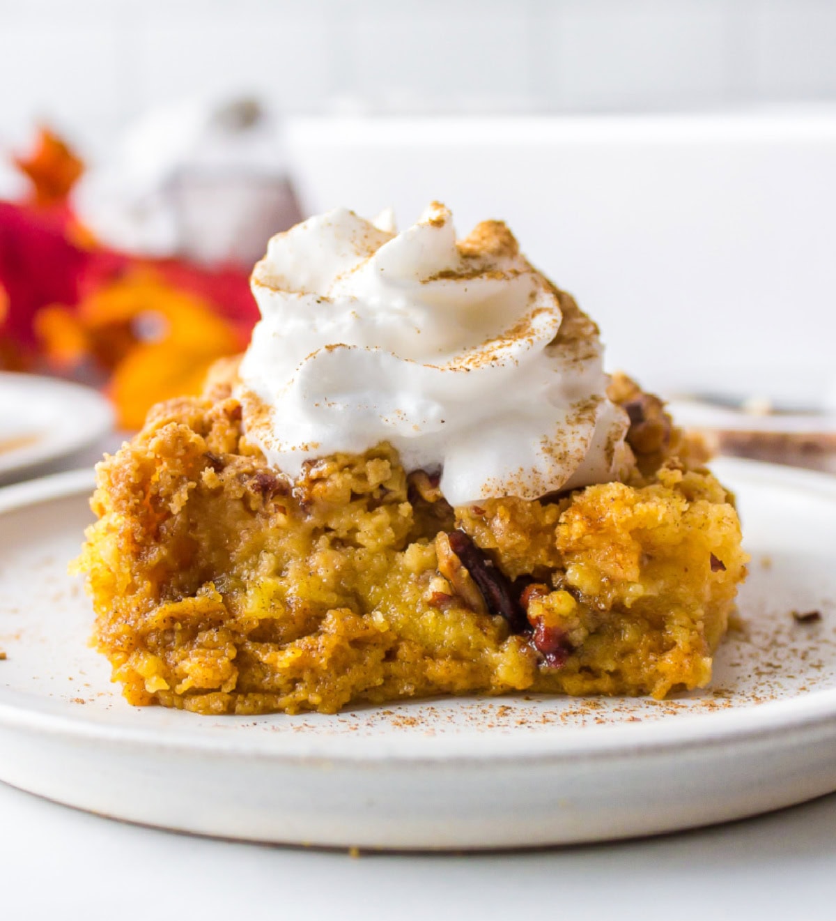 Pumpkin Dump Cake is a buttery pumpkin dessert cake. It’s pretty delicious and addicting. slice of pumpkin dump cake on plate with whipped cream