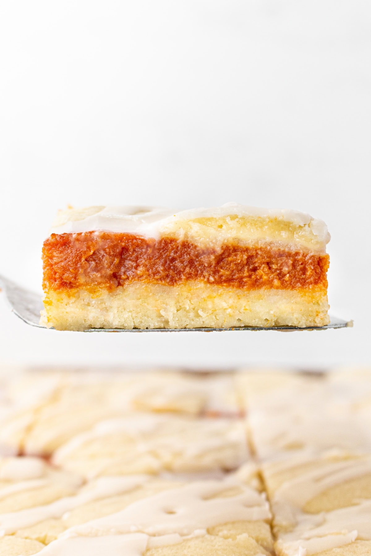 These Pumpkin Bars are delicious with pumpkin filling surrounded by two layers of flaky, buttery, sweet crust! Recipe from RecipeGirl.com. pumpkin bar on a spatula