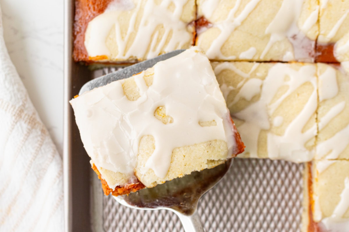 These Pumpkin Bars are delicious with pumpkin filling surrounded by two layers of flaky, buttery, sweet crust! Recipe from RecipeGirl.com. spatula holding pumpkin bar