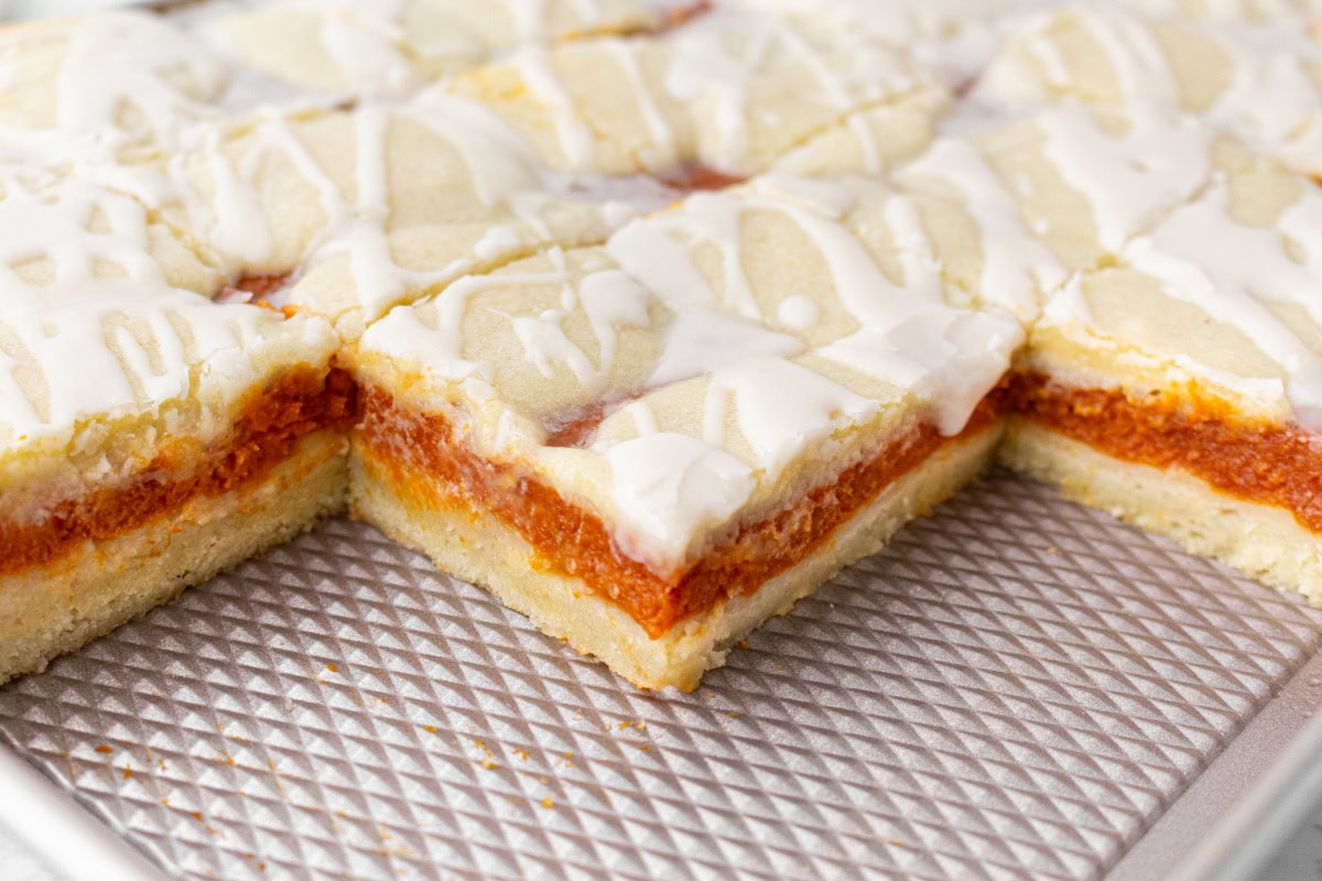 These Pumpkin Bars are delicious with pumpkin filling surrounded by two layers of flaky, buttery, sweet crust! Recipe from RecipeGirl.com. cut pieces of pumpkin bars