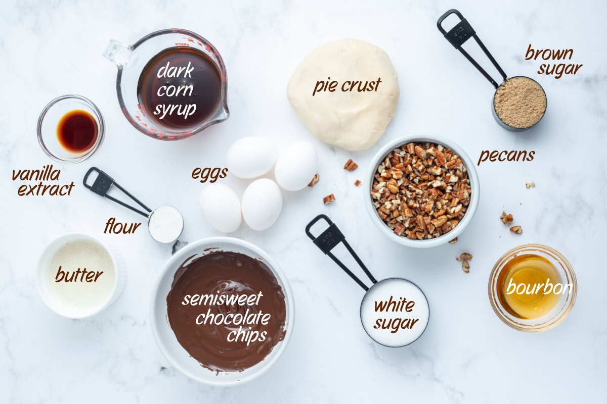 Rich Bourbon Chocolate Pecan Pie made with dark corn syrup, brown sugar, melted chocolate, and toasted pecans. A decadent holiday dessert that’s unforgettable! ingredients displayed for making bourbon chocolate pecan pie