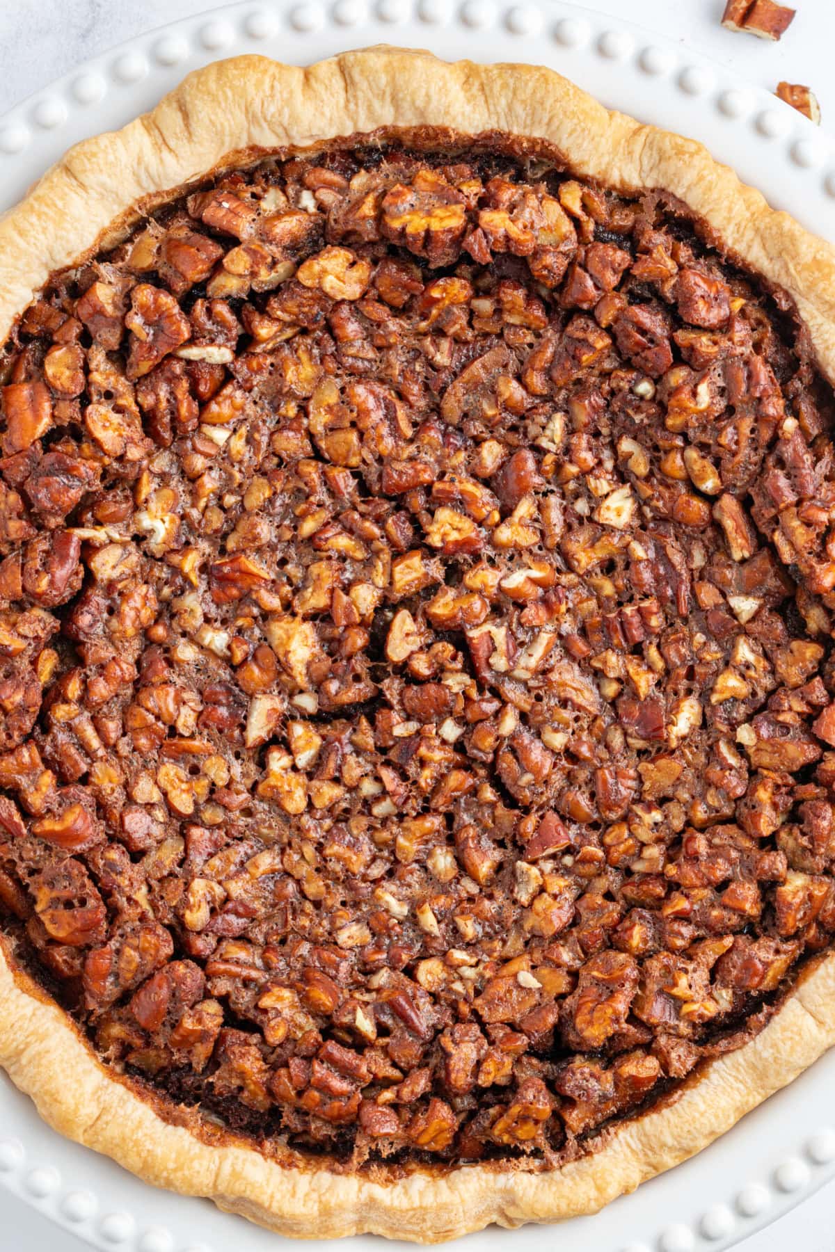 Rich Bourbon Chocolate Pecan Pie made with dark corn syrup, brown sugar, melted chocolate, and toasted pecans. A decadent holiday dessert that’s unforgettable! bourbon chocolate pecan pie close up over head shot