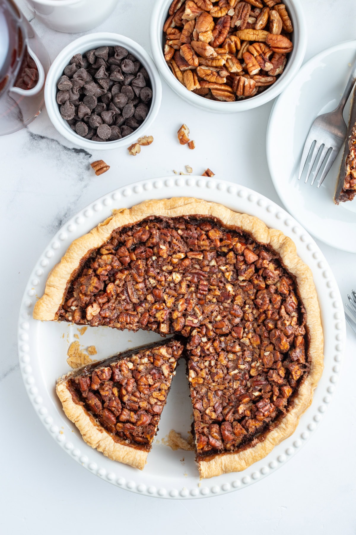 Rich Bourbon Chocolate Pecan Pie made with dark corn syrup, brown sugar, melted chocolate, and toasted pecans. A decadent holiday dessert that’s unforgettable! overhead shot of bourbon chocolate pecan pie with slices taken out of it
