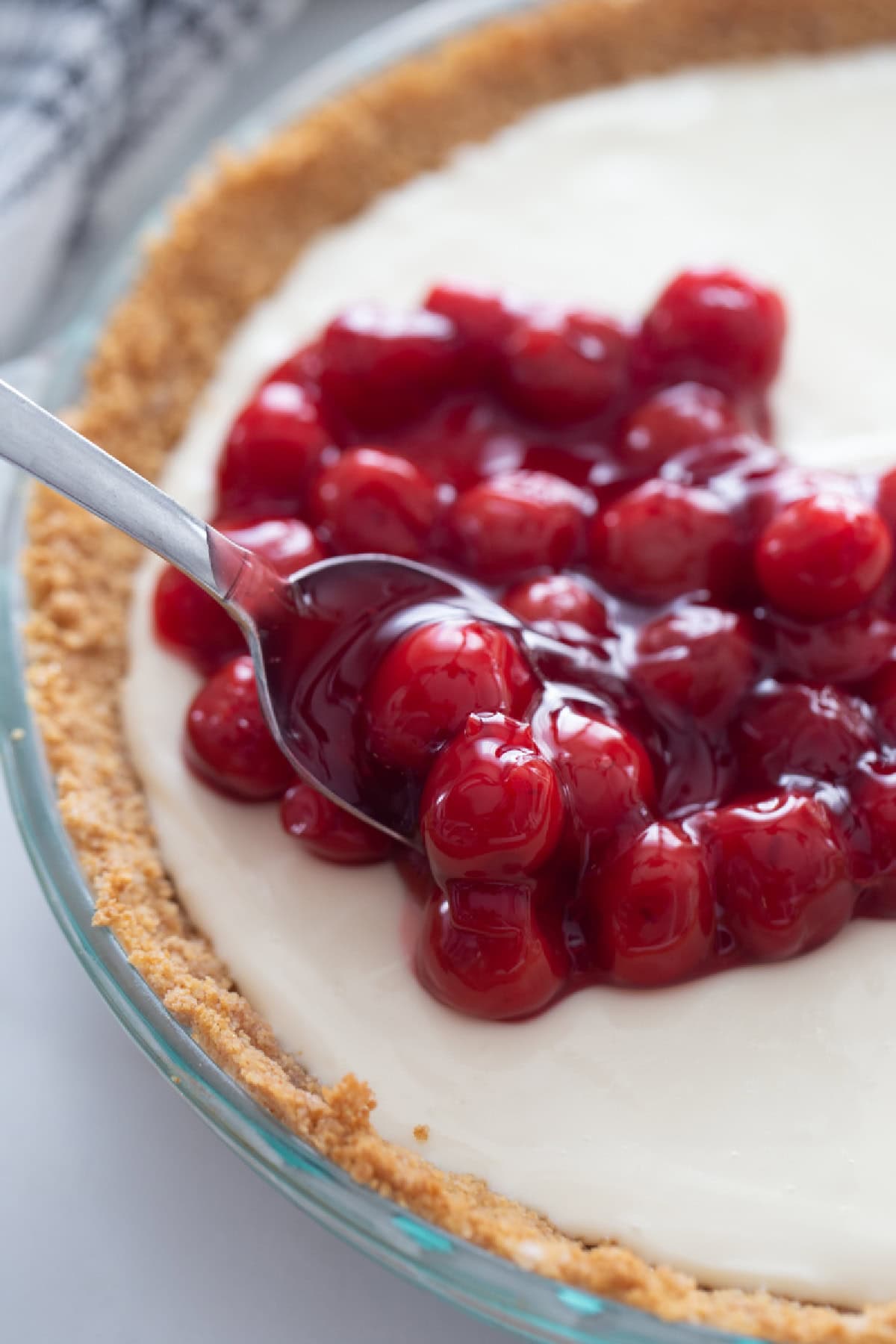 spooning cherries onto cream cheese layer of pie