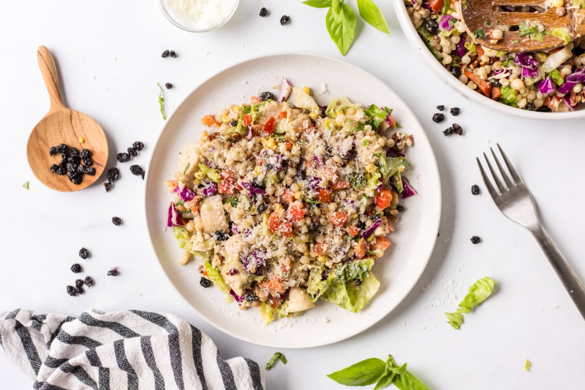 This Chopped Chicken and Couscous Salad with Sweet Basil Dressing is fresh, flavorful, and flexible! Swap turkey, wild rice, and cranberries for a fall twist. serving of chopped chicken and couscous salad on a plate