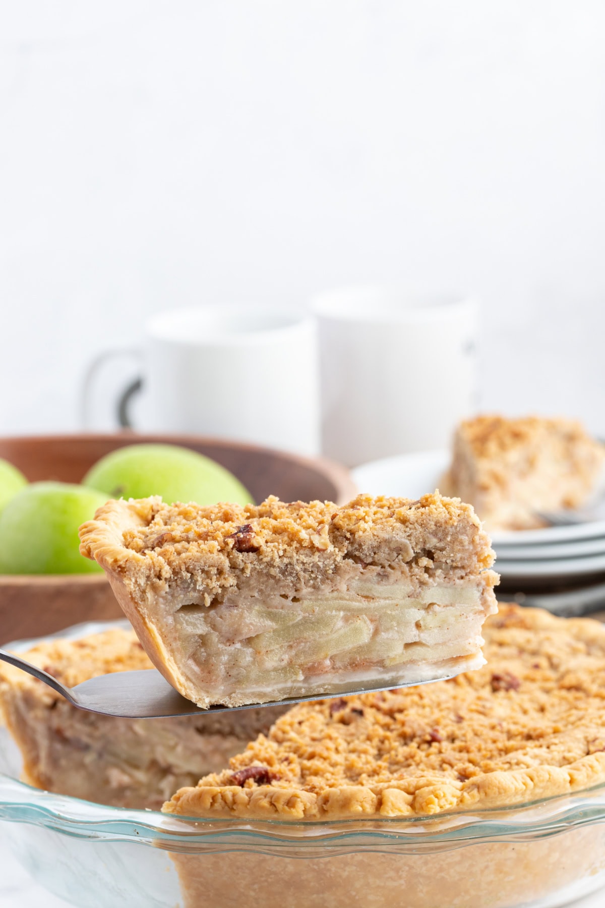 Homemade Dutch Apple Pie with buttery pecan streusel and cinnamon apples. Cozy, classic, and perfect for fall baking or holiday dessert tables. spatula taking slice of pie out of dutch apple pie