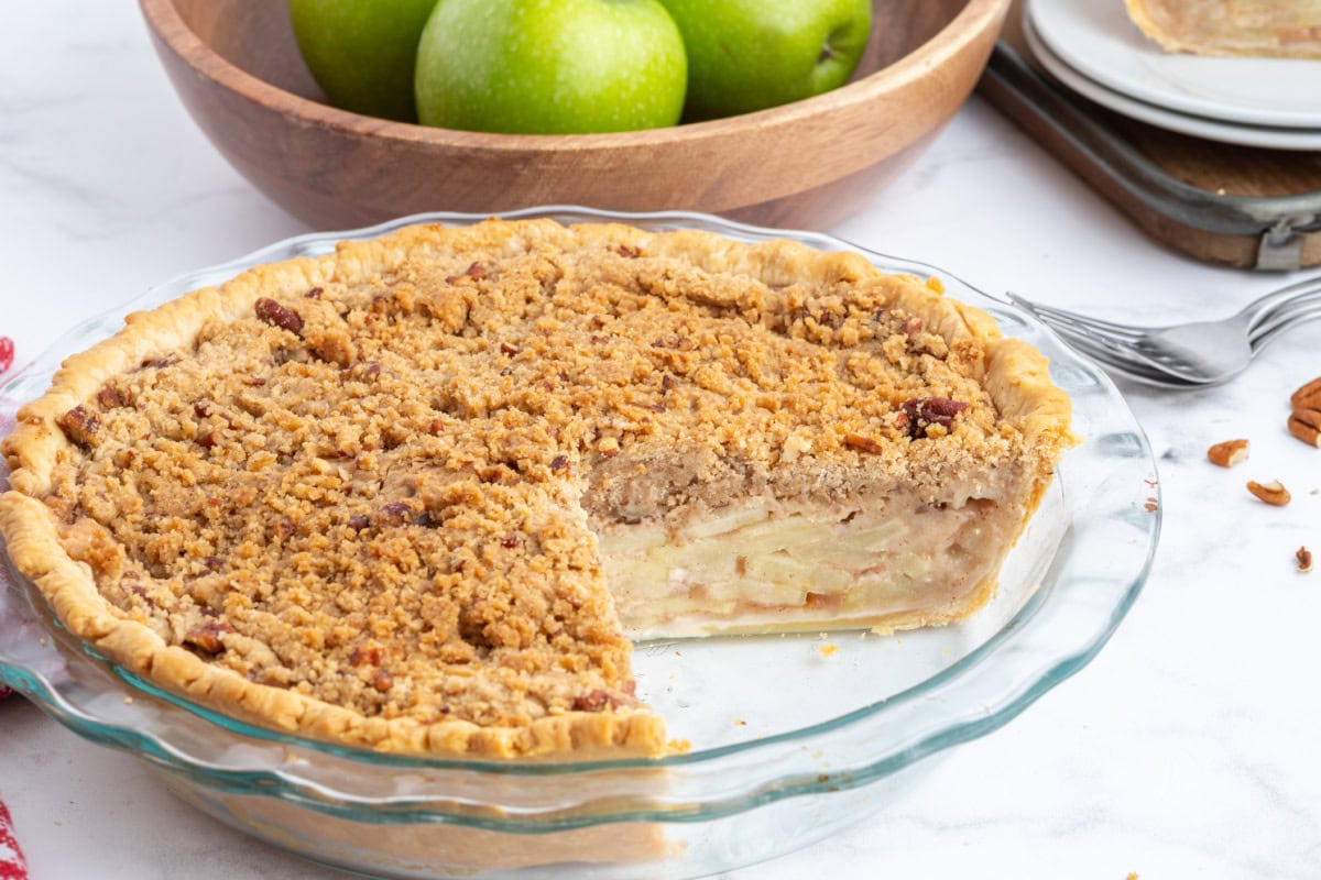 Homemade Dutch Apple Pie with buttery pecan streusel and cinnamon apples. Cozy, classic, and perfect for fall baking or holiday dessert tables. dutch apple pie with big slice taken out