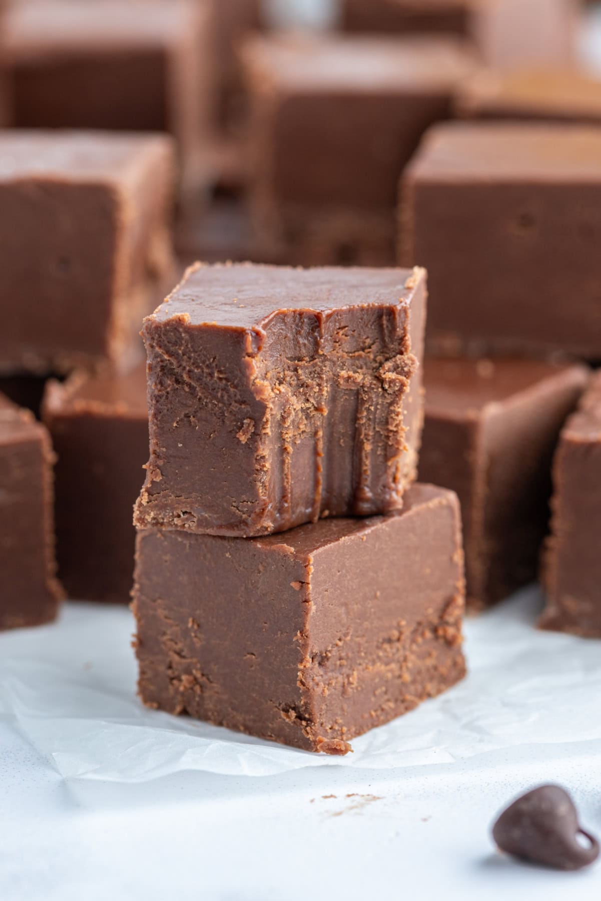 This Easy Microwave Kahlua Fudge has two chocolate layers, a rich Kahlua coffee flavor, and comes together in minutes. Perfect for holiday gifts and dessert trays! two pieces of fudge stacked with one bite taken out of it
