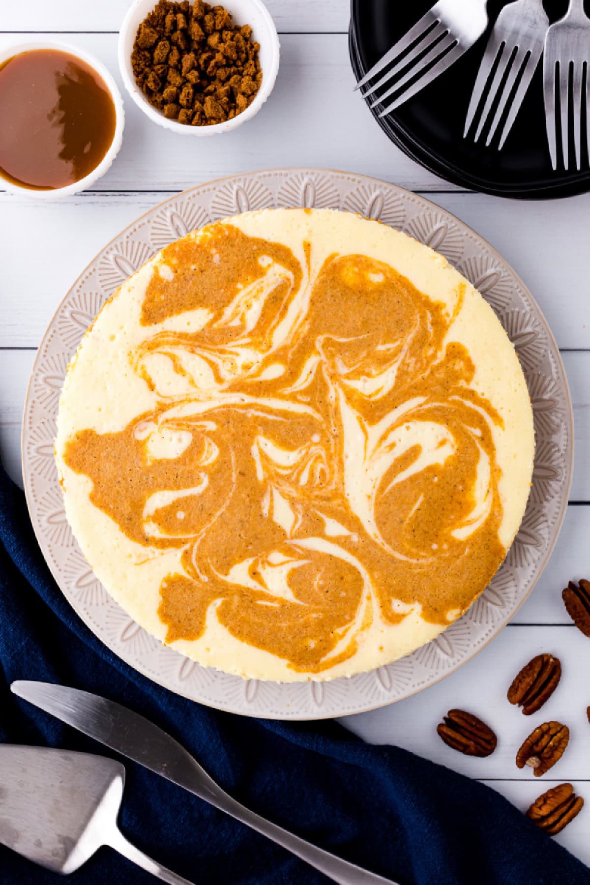 This creamy Pumpkin Swirl Cheesecake has a buttery gingersnap-pecan crust and a gorgeous marbled swirl of pumpkin and cheesecake. Perfect for Thanksgiving or any cozy fall celebration! Top with caramel or whipped cream for an irresistible dessert everyone will love. overhead shot of pumpkin swirl cheesecake