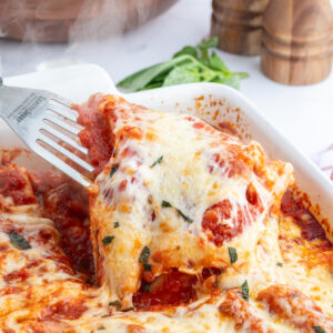 spatula taking cheese manicotti out of baking dish