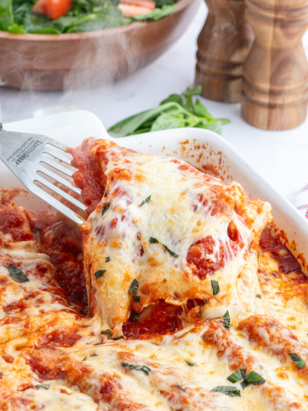 spatula taking cheese manicotti out of baking dish