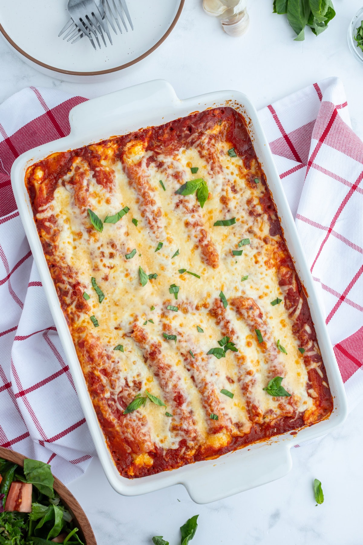 This classic Cheese Manicotti is stuffed with a creamy three-cheese filling, covered in marinara, and baked until bubbly. Easy, comforting, and perfect for family dinners! overhead shot of cheese manicotti in a white baking dish
