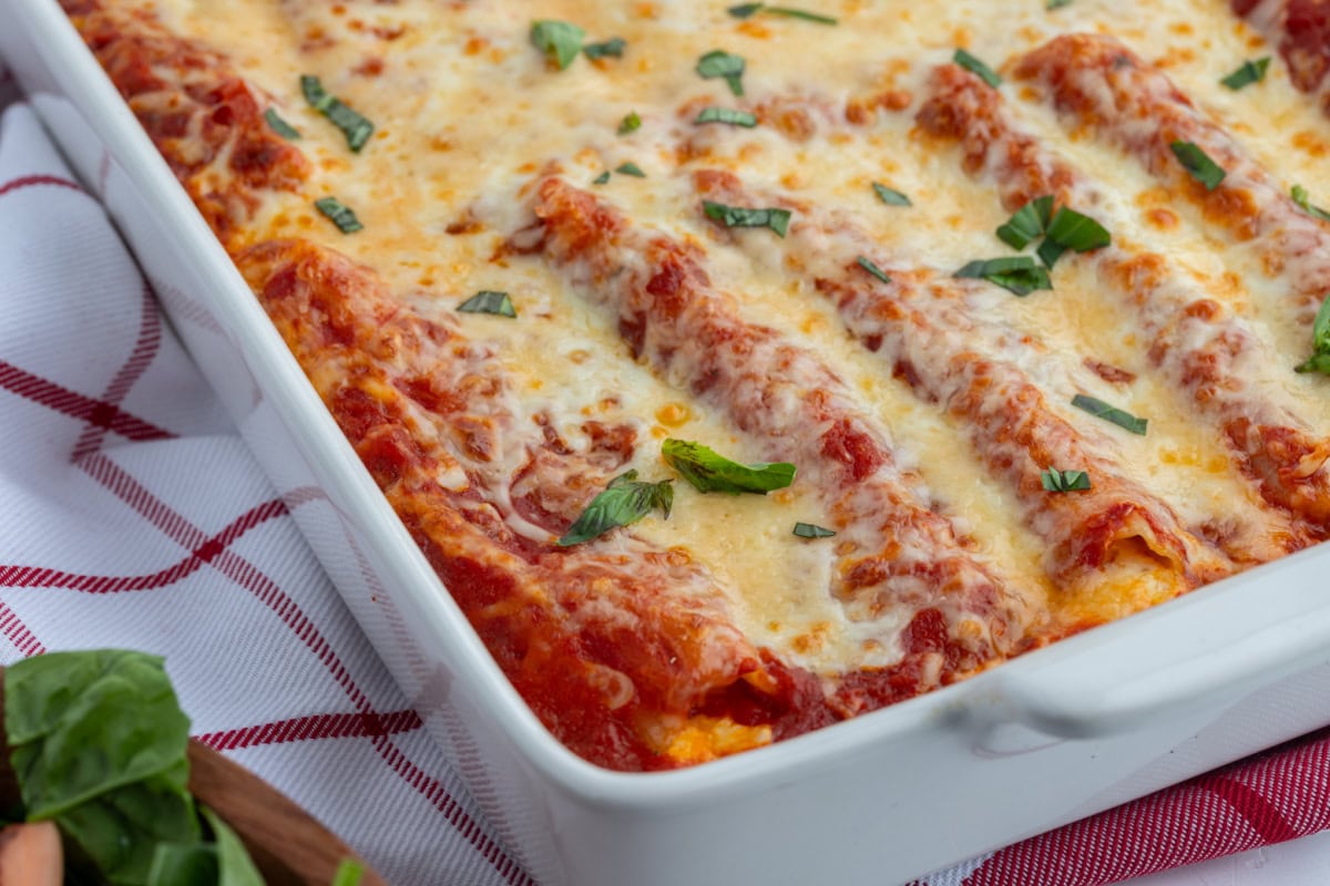 This classic Cheese Manicotti is stuffed with a creamy three-cheese filling, covered in marinara, and baked until bubbly. Easy, comforting, and perfect for family dinners! cheese manicotti in a white baking dish