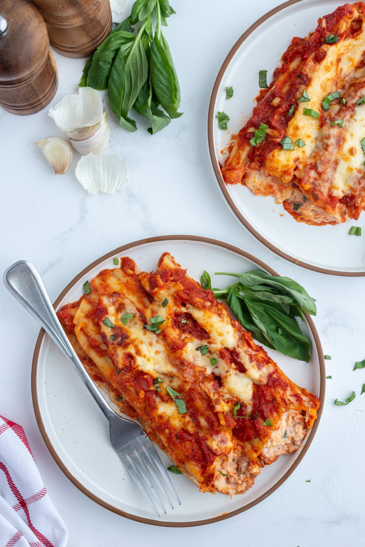 This classic Cheese Manicotti is stuffed with a creamy three-cheese filling, covered in marinara, and baked until bubbly. Easy, comforting, and perfect for family dinners! servings of cheese manicotti on two plates