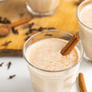 coquito in a glass with a cinnamon stick
