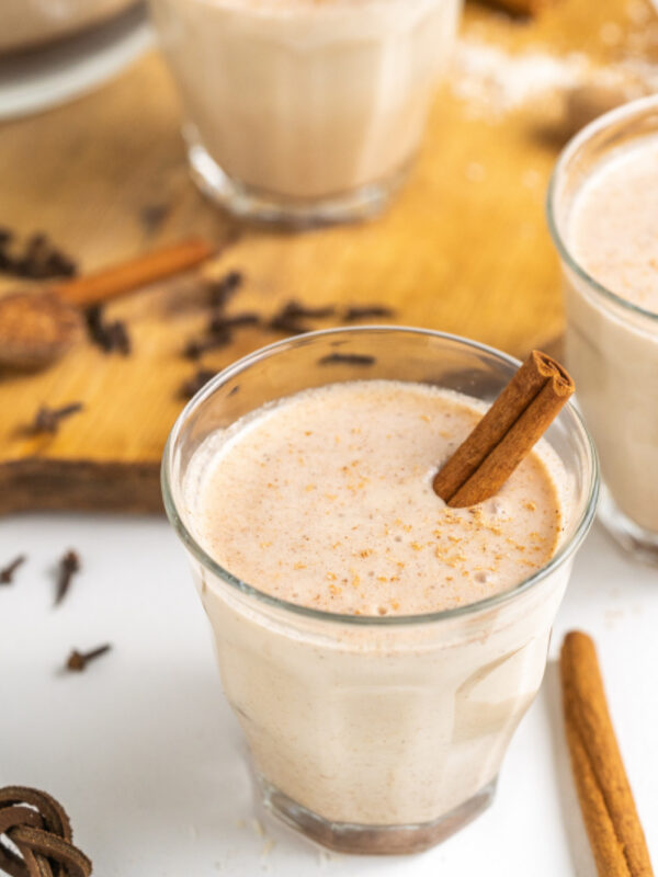 coquito in a glass with a cinnamon stick