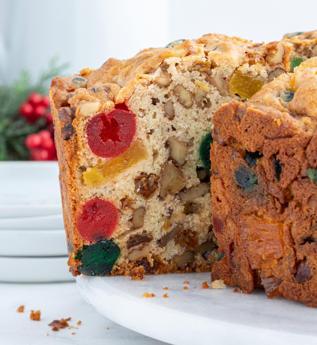 This homemade fruitcake is rich, moist, and loaded with candied fruit and nuts. A traditional Christmas dessert that bakes beautifully and slices perfectly every time. taking slice of fruitcake out of cake