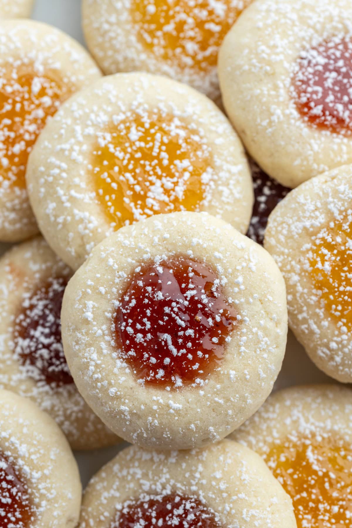 These soft and buttery Jam Thumbprint Cookies are filled with your favorite fruit jam and baked to golden perfection. A classic holiday cookie that’s easy, nostalgic, and perfect for gifting! close up jam thumbprint cookies