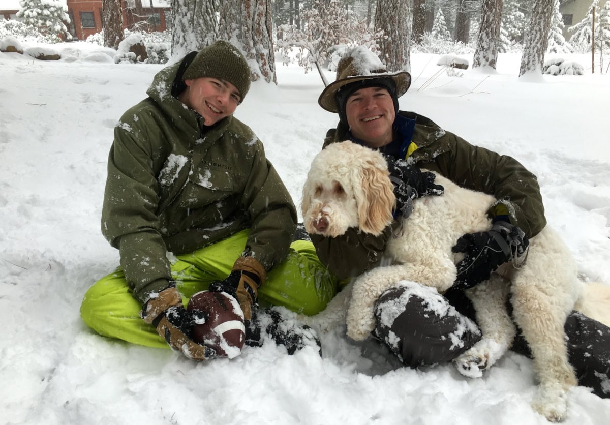 two men and a dog in the snow