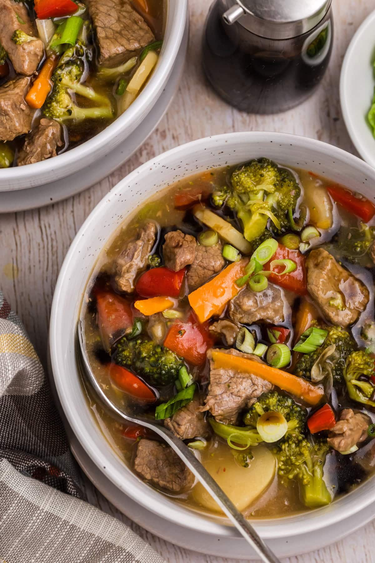 This Beef and Vegetable Stew is comfort food with a twist! Tender beef simmers in a savory soy-ginger broth with carrots, broccoli, red bell pepper, and water chestnuts. Perfect for cool nights and great for leftovers! white bowls of beef and vegetable stew