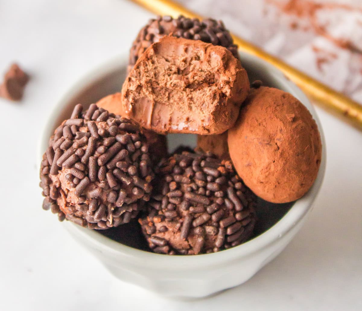 bowl of chocolate truffles with one having a bite taken out of it