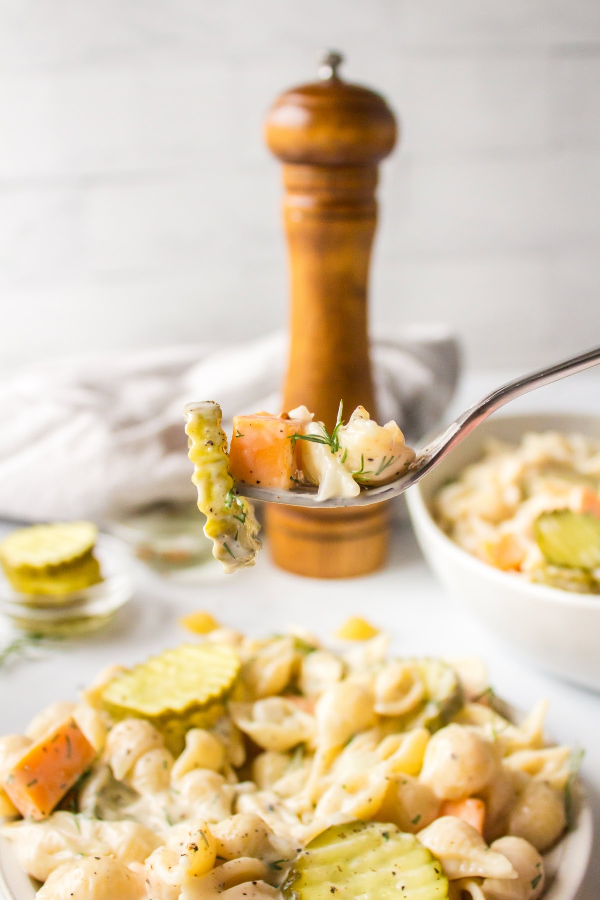 Dill Pickle Pasta Salad is the ultimate creamy, tangy side dish! Shell pasta is soaked in pickle juice, then tossed with cheddar, fresh dill, and a creamy dressing. Perfect for BBQs, potlucks, and summer parties! fork full of dill pickle pasta salad