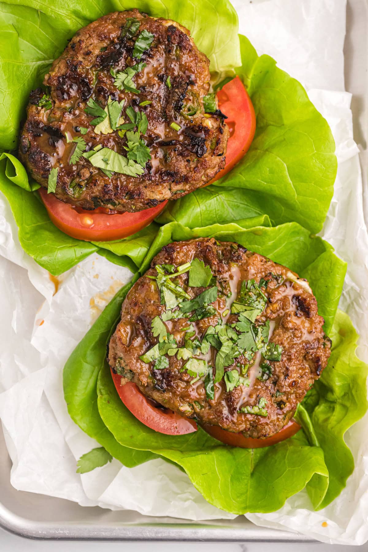 These Healthy Turkey Burgers with Orange Ginger Glaze are juicy, bright, and full of fresh flavor. Lean turkey meets a tangy homemade citrus glaze — perfect for easy dinners! two healthy turkey burger patties with lettuce and tomato