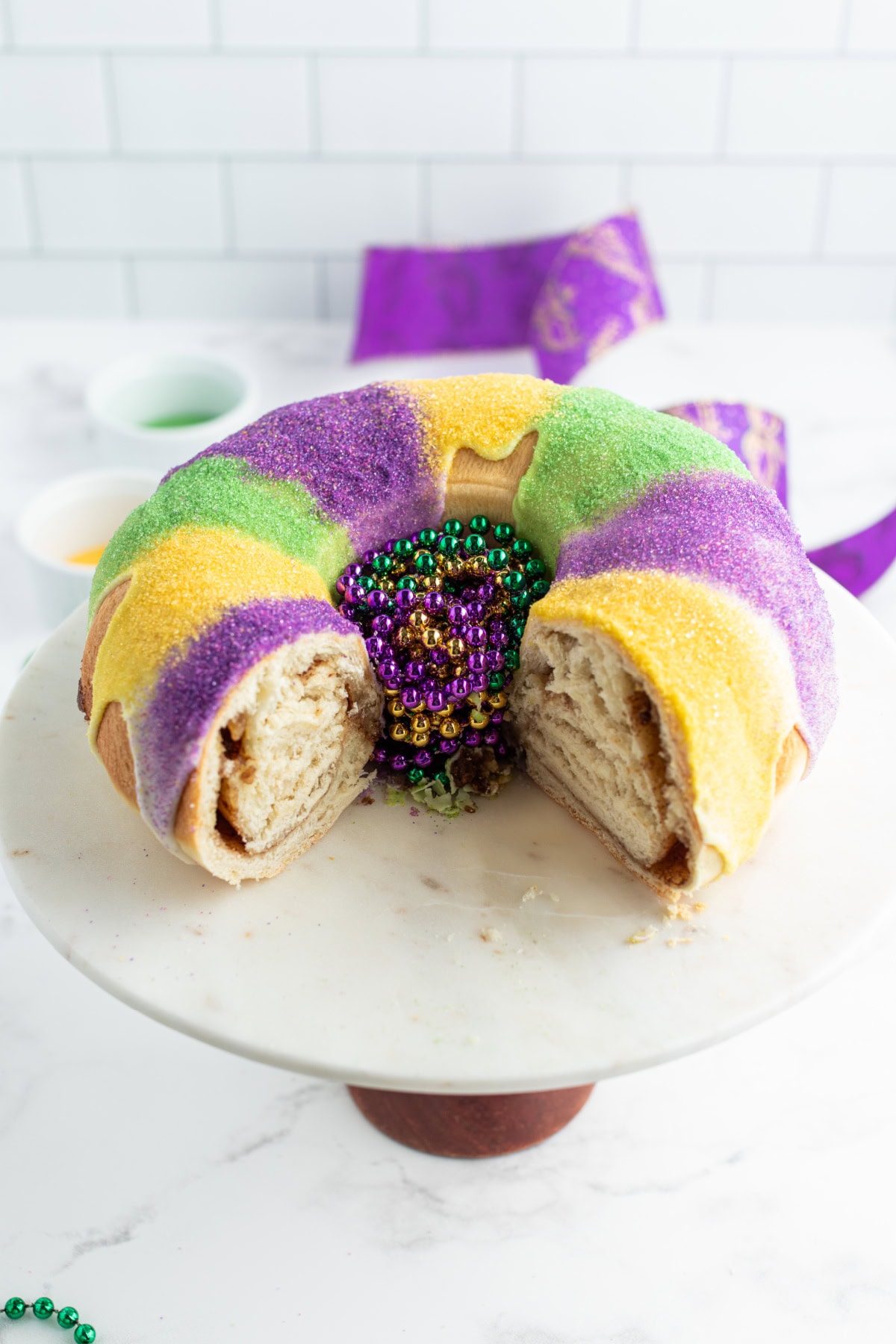 king cake with big slice taken out of it on cake stand