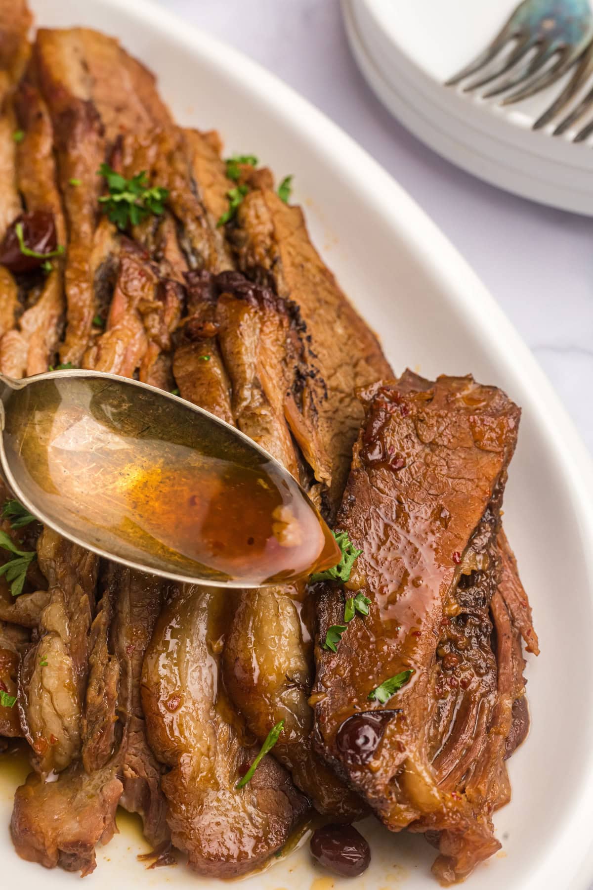 spooning sauce onto slices of rabbi's wife's brisket