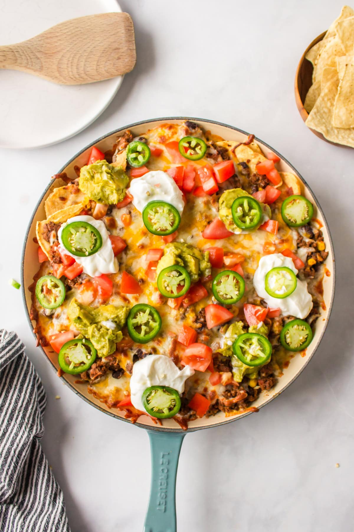 Skillet Nachos 🧀🌶️ The easiest way to make nachos! Tortilla chips topped with seasoned beef, Rotel, black beans, corn, and melty Colby-Jack cheese—add sour cream, guacamole & jalapeños! skillet nachos in pan