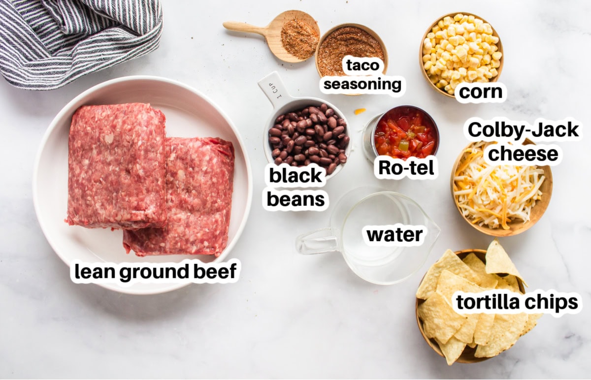 Skillet Nachos 🧀🌶️ The easiest way to make nachos! Tortilla chips topped with seasoned beef, Rotel, black beans, corn, and melty Colby-Jack cheese—add sour cream, guacamole & jalapeños! ingredients displayed for making skillet nachos