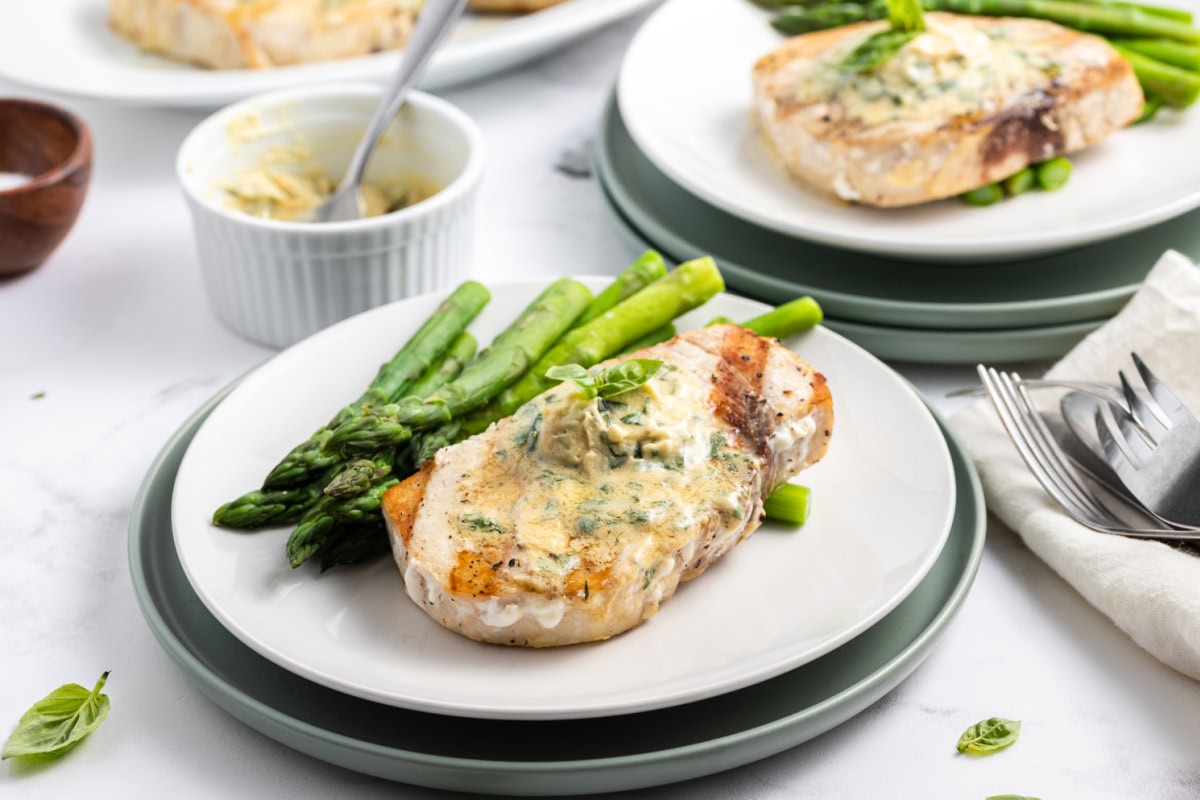grilled swordfish with mustard basil butter and asparagus on plates