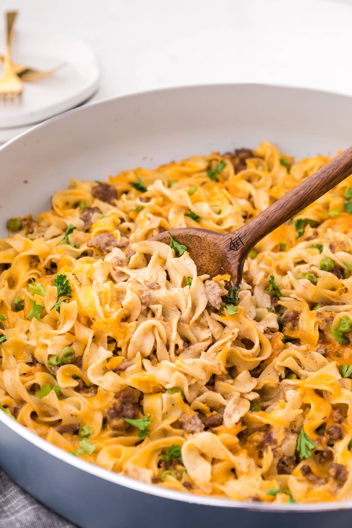 This Ground Beef Stroganoff is creamy, cheesy, and loaded with beef and noodles in a rich sauce. A cozy, easy dinner idea! spoon in pan of ground beef stroganoff