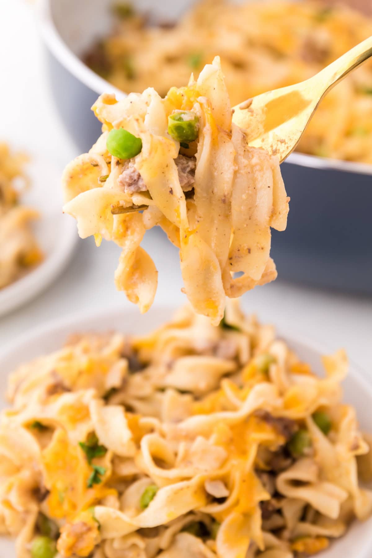 This Ground Beef Stroganoff is creamy, cheesy, and loaded with beef and noodles in a rich sauce. A cozy, easy dinner idea! fork holding up taste of ground beef stroganoff