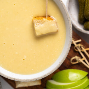 toothpick with bread in bowl of cheese fondue