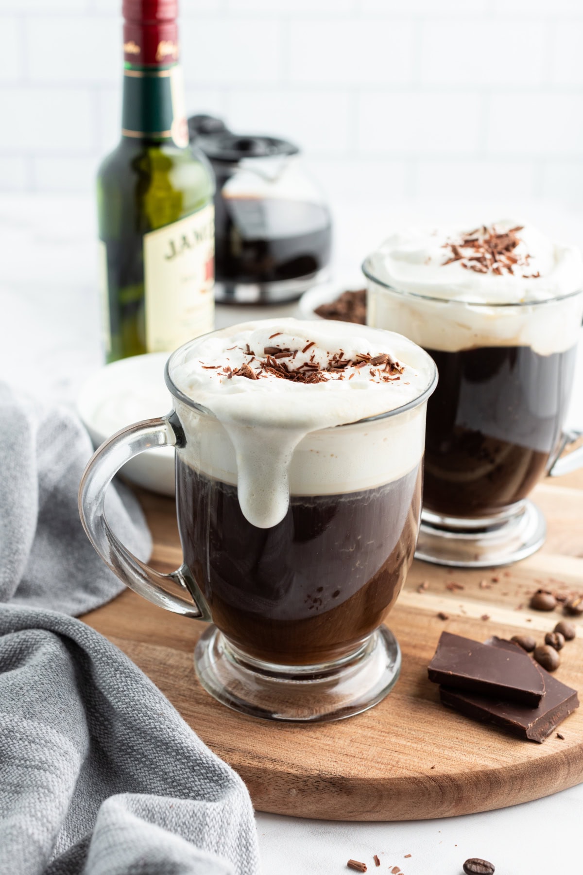 Learn how to make Irish Coffee—hot coffee, Irish whiskey, brown sugar, and whipped cream. A cozy classic cocktail. whipped cream dripping down side of mug of irish coffee