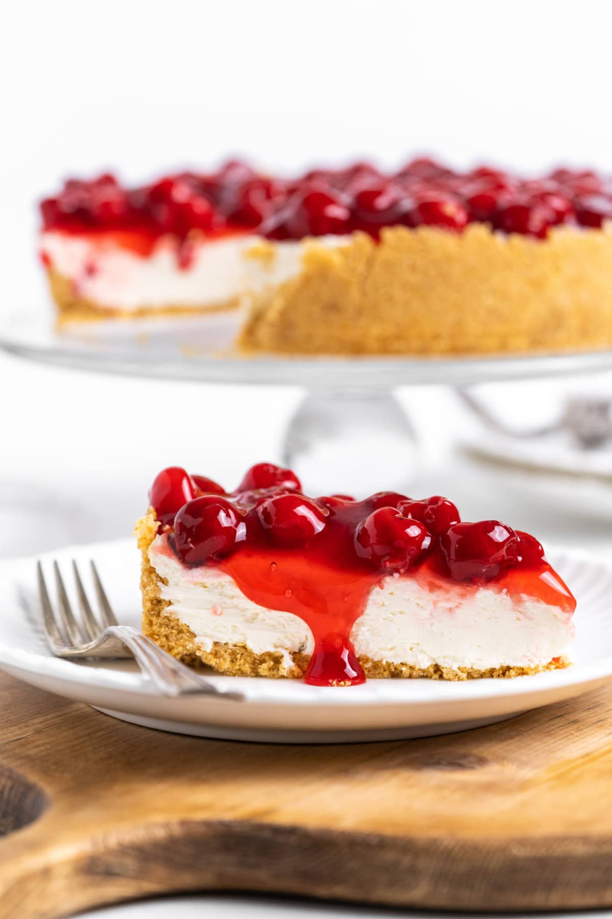 This easy No Bake Cherry Cheesecake has a buttery graham cracker crust, fluffy cream cheese filling, and sweet cherry topping. Perfect make-ahead dessert! slice of no bake cherry cheesecake on plate with fork