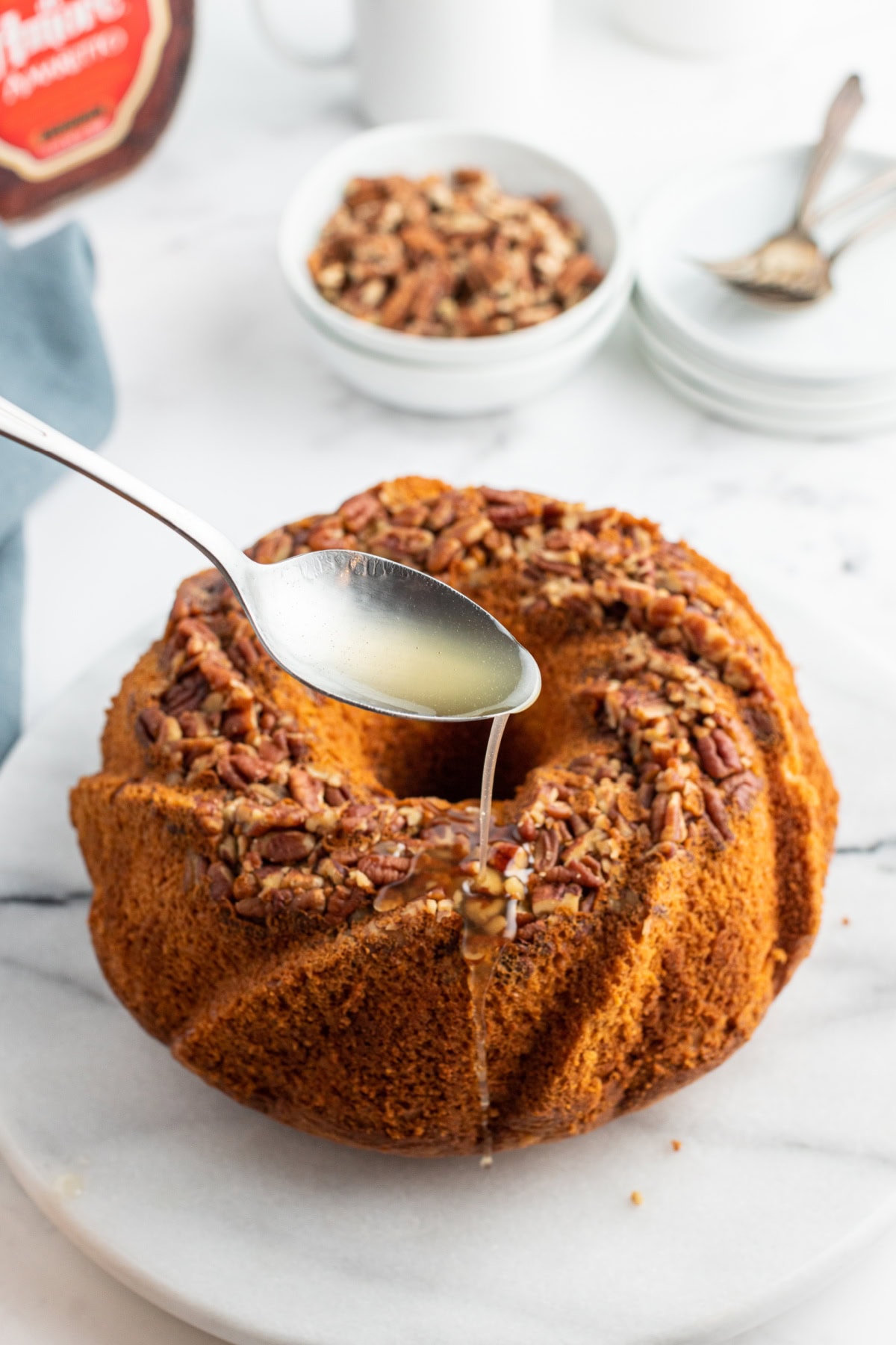 spooning syrup over amaretto bundt cake