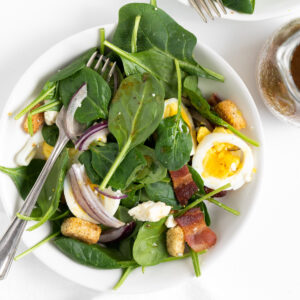 baby spinach salad on a white plate with a fork