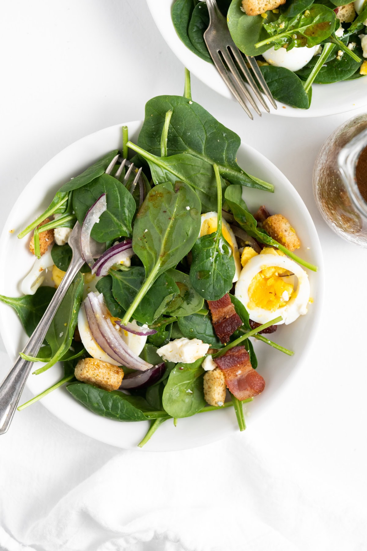 baby spinach salad on a white plate with a fork