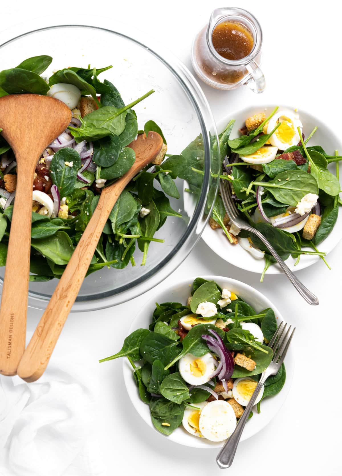 bowl of baby spinach salad and two servings on plates
