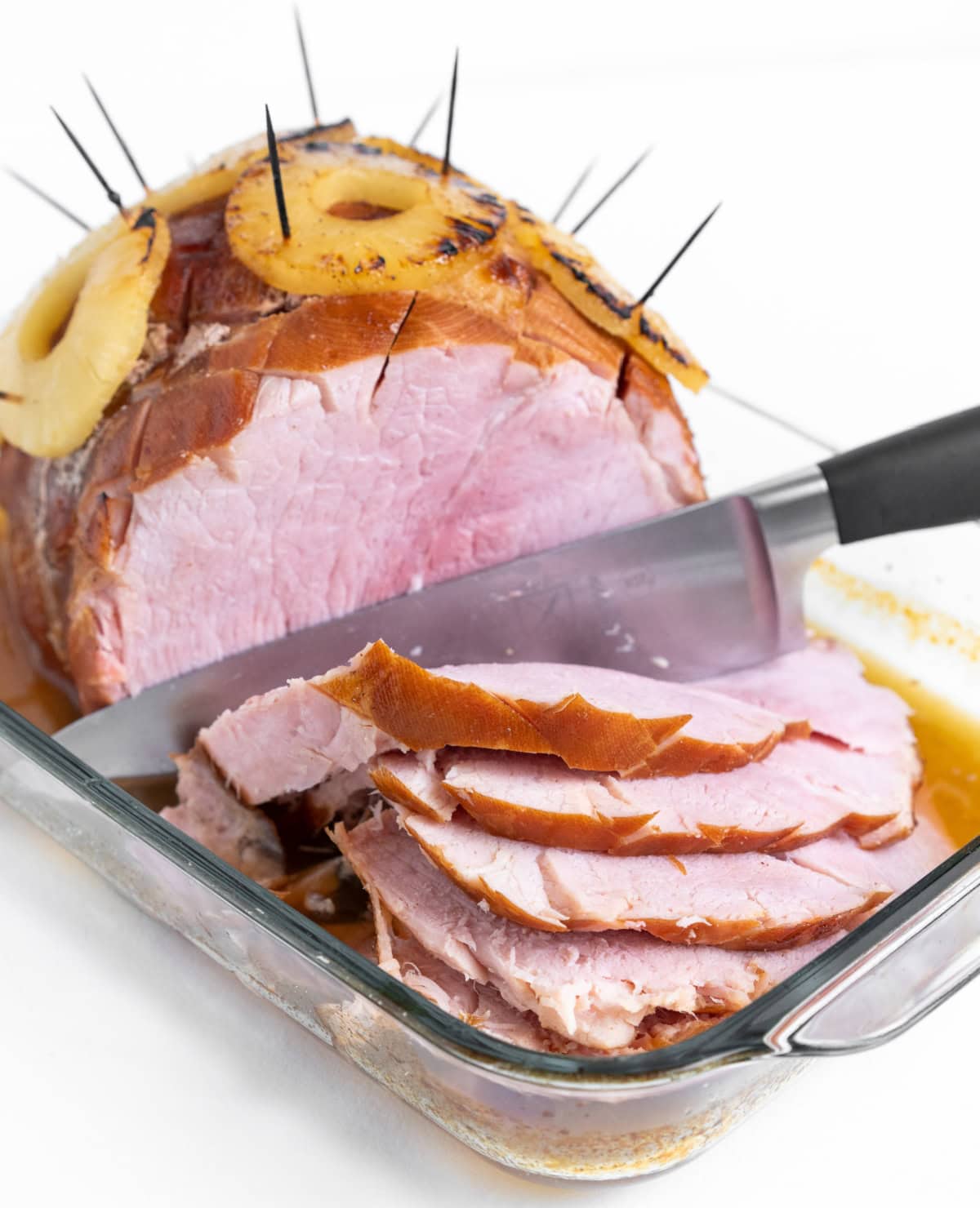 knife slicing baked ham in dish
