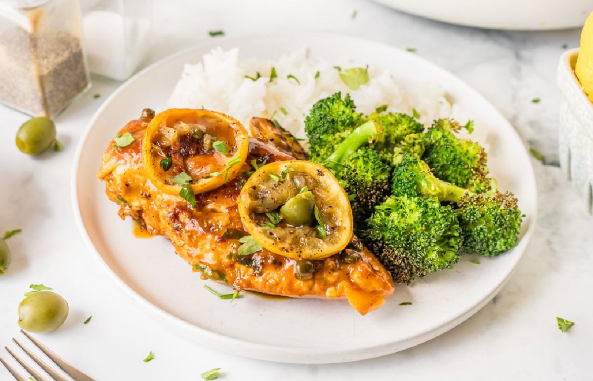 chicken with roasted lemons served on a white plate with broccoli