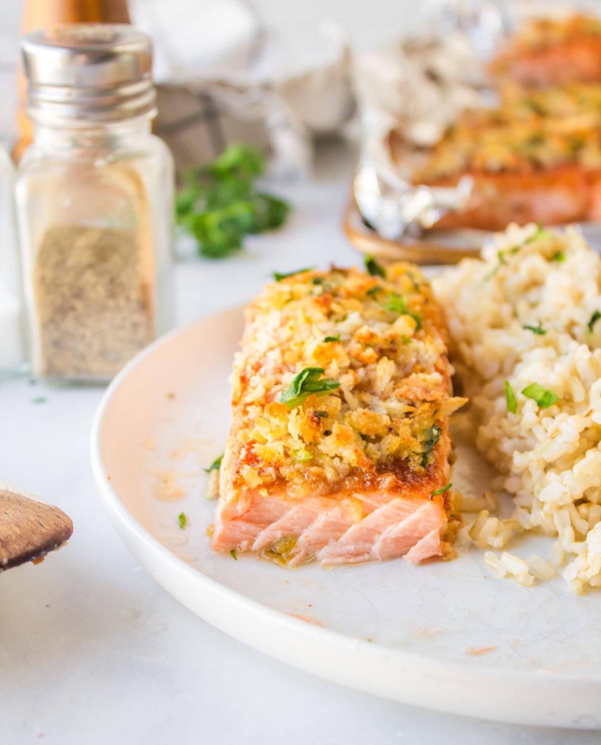 Easy Baked Salmon with a crispy breadcrumb topping and sweet savory flavor. A quick and delicious salmon dinner ready in minutes. salmon on plate with bite taken out of it