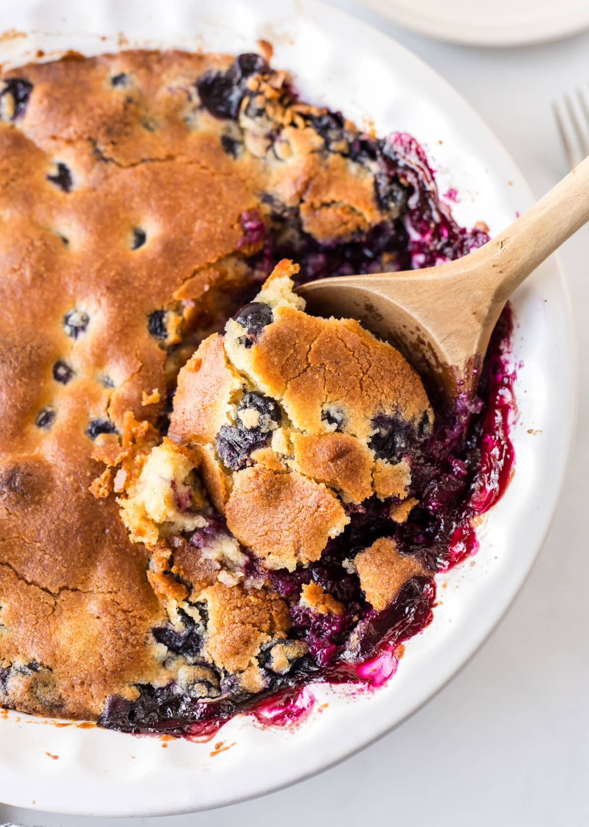 blueberry cobbler with wooden spoon in it