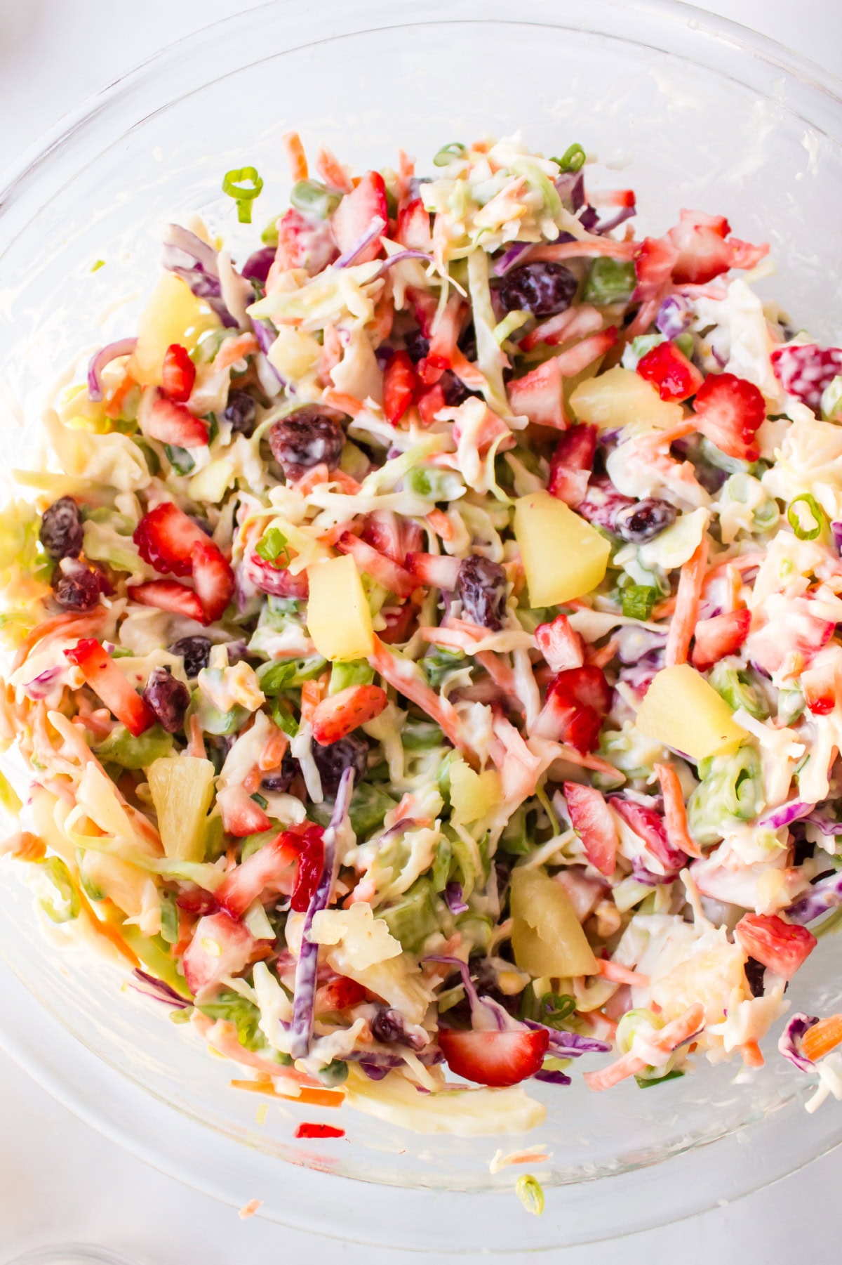Fruity Coleslaw with strawberries, pineapple and coconut is a sweet, tangy and crunchy side dish perfect for BBQs and summer gatherings. close up bowl of fruity coleslaw