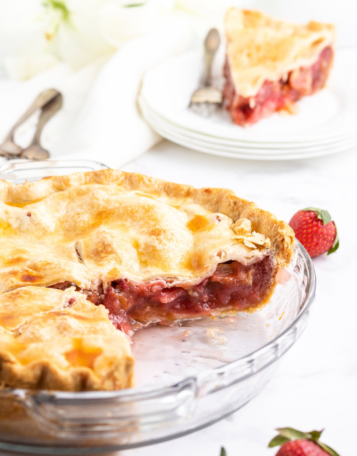 strawberry rhubarb pie with big slice taken out of it