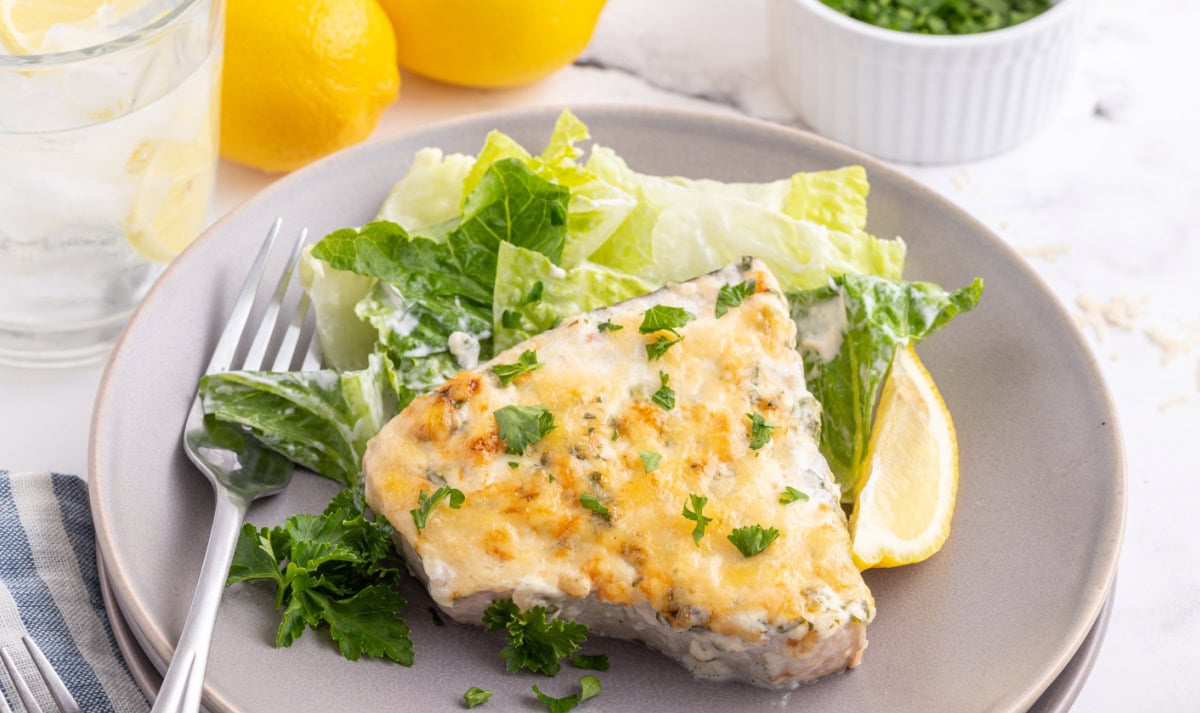 Swordfish parmesan with a golden, savory topping. An easy, fresh seafood dinner ready in under 30 minutes! swordfish parmesan served on a plate with salad