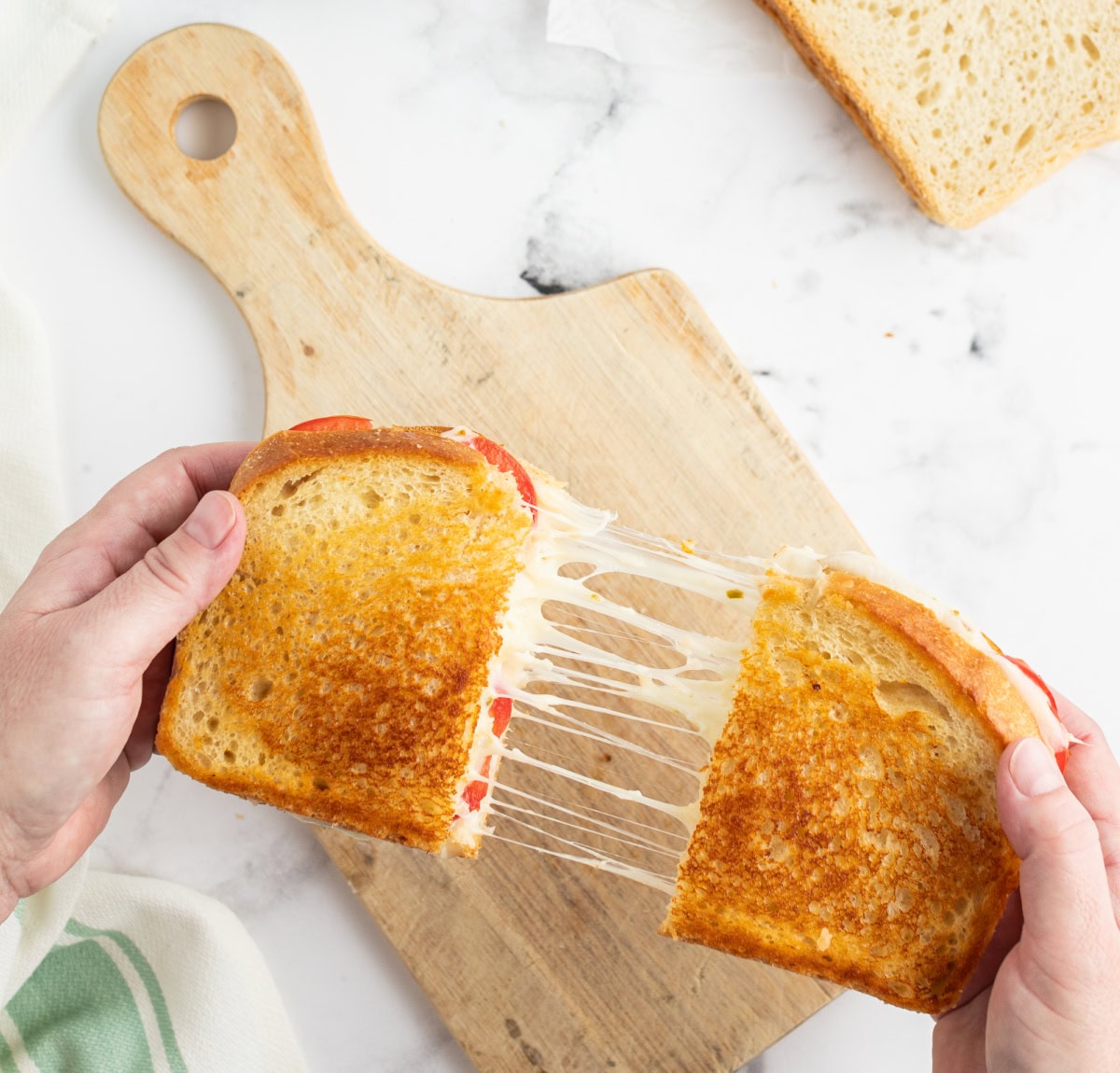 hands pulling apart a tomato grilled cheese